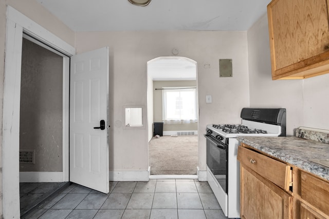 kitchen with visible vents, light tile patterned floors, arched walkways, and white gas range