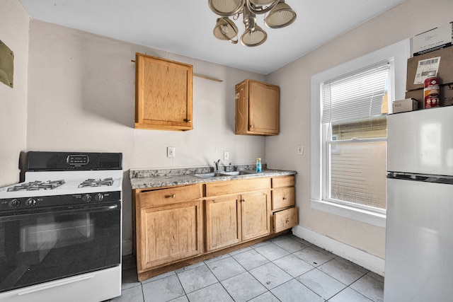 kitchen featuring light tile patterned floors, gas stove, freestanding refrigerator, a sink, and light countertops