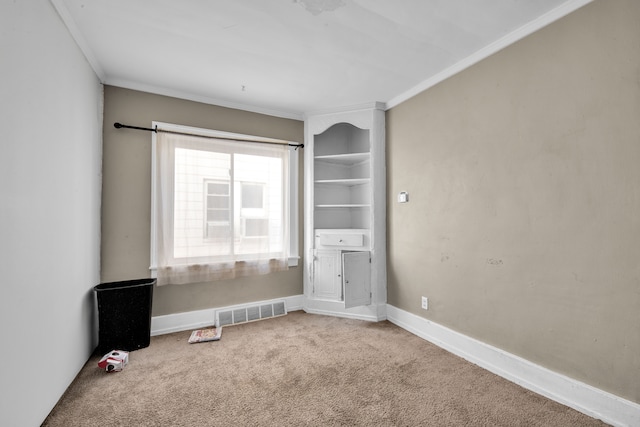 carpeted empty room featuring crown molding, baseboards, and visible vents