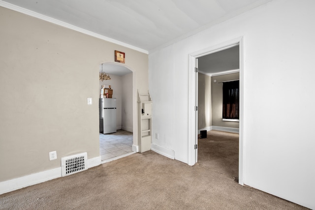 unfurnished room featuring baseboards, visible vents, carpet floors, arched walkways, and ornamental molding