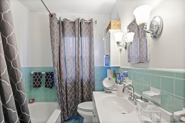 full bath with vanity, shower / bathtub combination with curtain, wainscoting, tile walls, and toilet