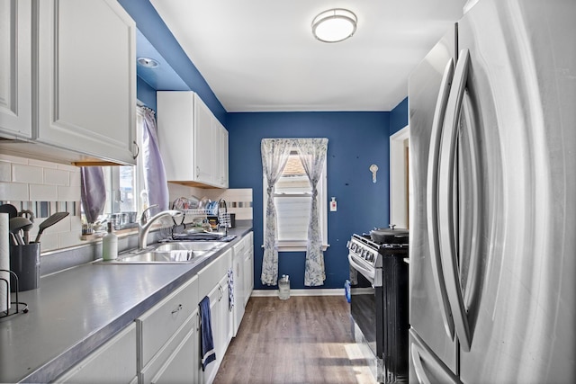 kitchen featuring tasteful backsplash, appliances with stainless steel finishes, dark wood-style floors, white cabinets, and a sink