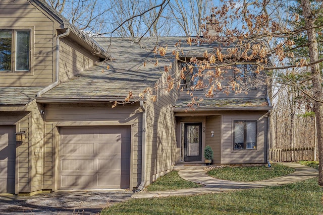 view of front facade featuring an attached garage, a chimney, and a shingled roof