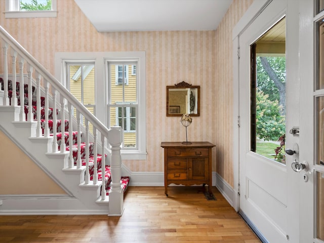 doorway to outside featuring a wealth of natural light, baseboards, wood finished floors, and wallpapered walls