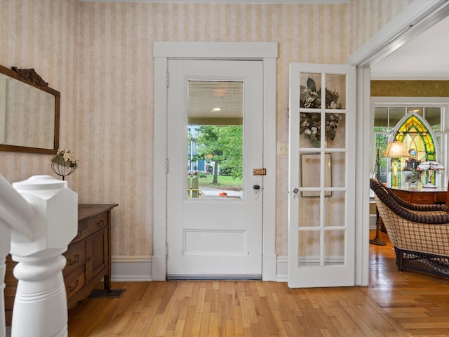 doorway featuring baseboards, light wood-style floors, and wallpapered walls