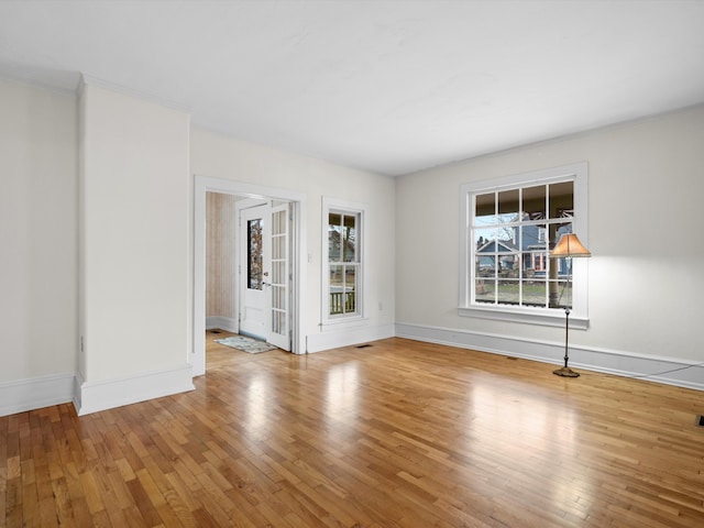 empty room featuring visible vents, crown molding, baseboards, and hardwood / wood-style flooring