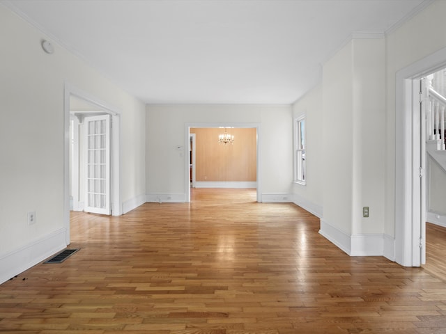 unfurnished living room featuring visible vents, baseboards, light wood-type flooring, and an inviting chandelier