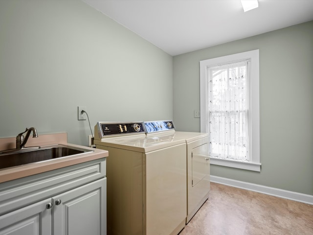 washroom with a sink, baseboards, cabinet space, and washing machine and dryer