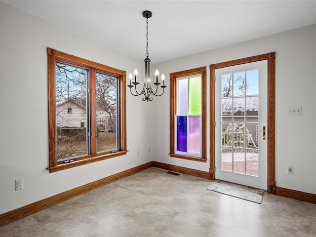 unfurnished dining area with visible vents, an inviting chandelier, concrete flooring, and baseboards