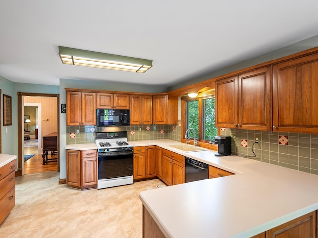 kitchen featuring black appliances, light countertops, brown cabinets, and a sink