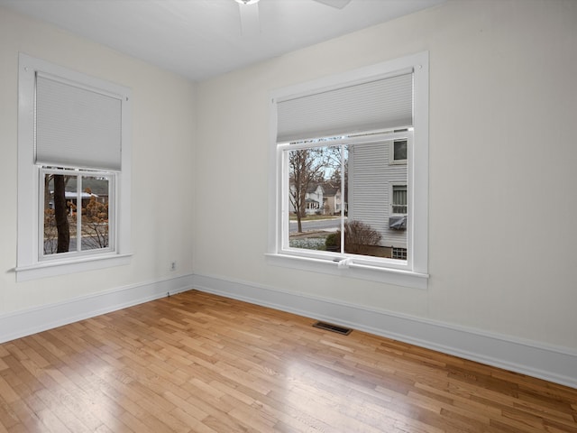 unfurnished room featuring visible vents, a ceiling fan, baseboards, and hardwood / wood-style floors