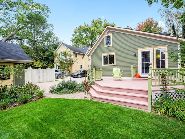 rear view of property featuring a lawn, a deck, and fence