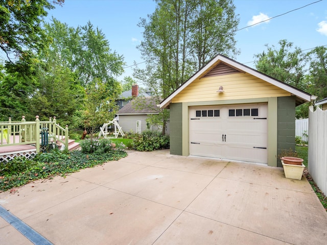 detached garage with concrete driveway and fence