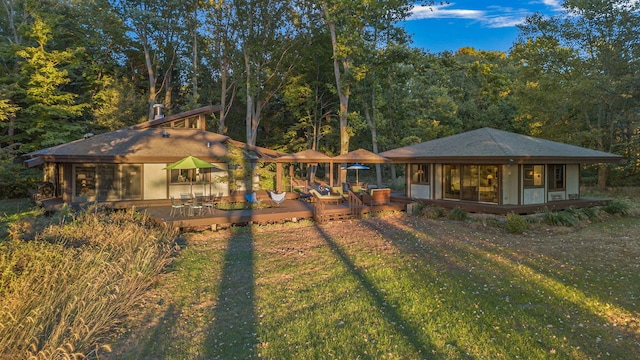 back of house with a wooded view, an outdoor structure, and a yard