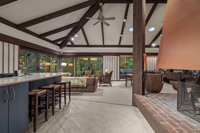 sunroom featuring rail lighting, lofted ceiling with beams, and a ceiling fan