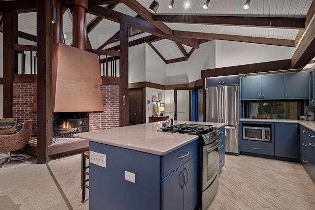 kitchen with appliances with stainless steel finishes, light countertops, blue cabinets, and a lit fireplace