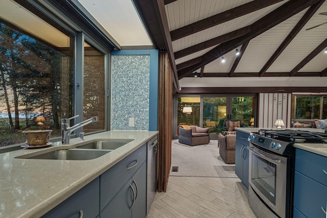 kitchen featuring a sink, blue cabinetry, lofted ceiling with beams, stainless steel appliances, and light countertops