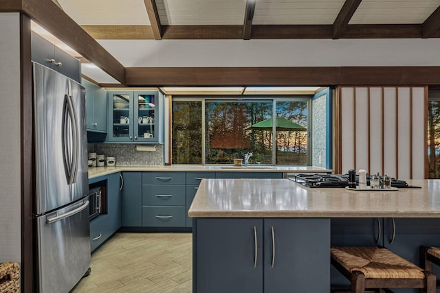 kitchen with decorative backsplash, a sink, light wood-style floors, appliances with stainless steel finishes, and glass insert cabinets