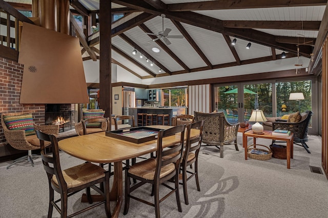 dining room with a brick fireplace, beamed ceiling, high vaulted ceiling, and light carpet