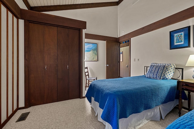 bedroom featuring a closet, visible vents, lofted ceiling with beams, and carpet floors