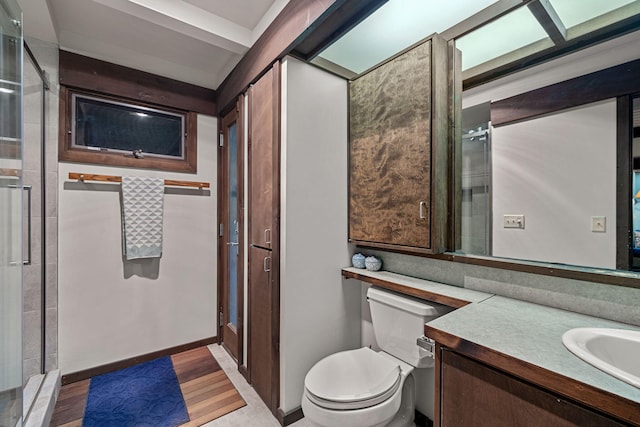 bathroom featuring a shower with shower door, toilet, wood finished floors, and vanity