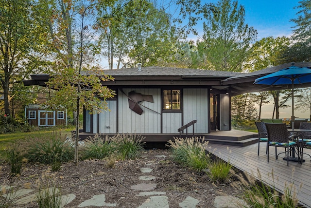 back of house with an outdoor structure and roof with shingles