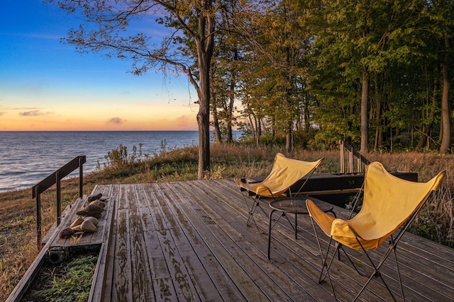 deck at dusk featuring a water view