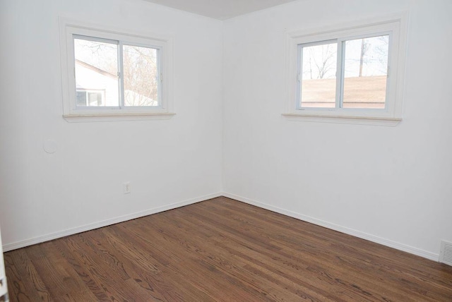 empty room with baseboards, a healthy amount of sunlight, and dark wood-style floors