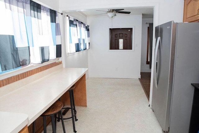 kitchen with a kitchen bar, light countertops, a ceiling fan, and freestanding refrigerator