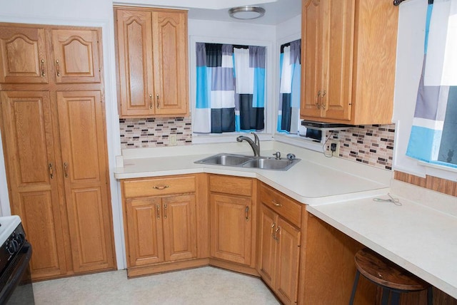 kitchen featuring light countertops, range, backsplash, and a sink