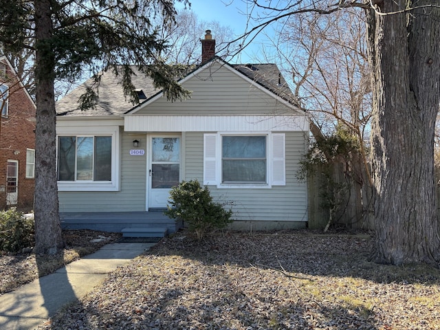 bungalow-style house featuring a chimney and a shingled roof