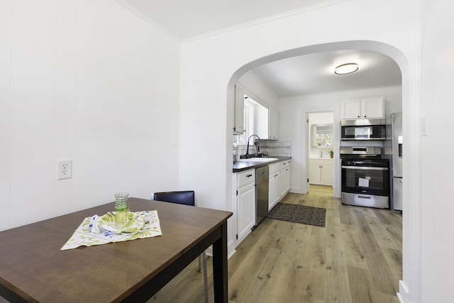 kitchen with arched walkways, appliances with stainless steel finishes, white cabinetry, and a sink