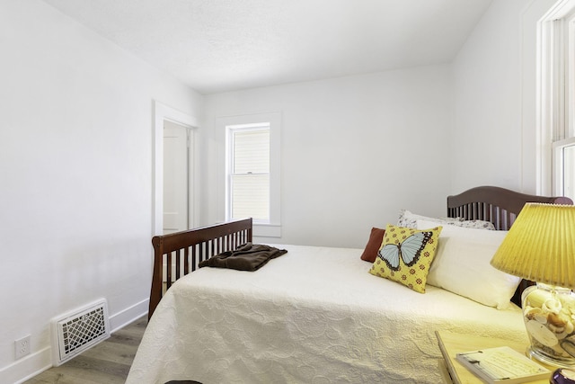 bedroom with visible vents, baseboards, and wood finished floors