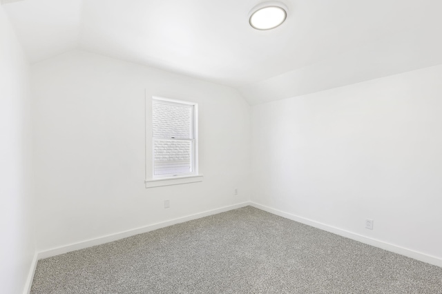 spare room with baseboards, lofted ceiling, and carpet floors