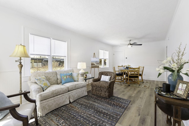 living area with light wood-type flooring, a textured ceiling, and a ceiling fan