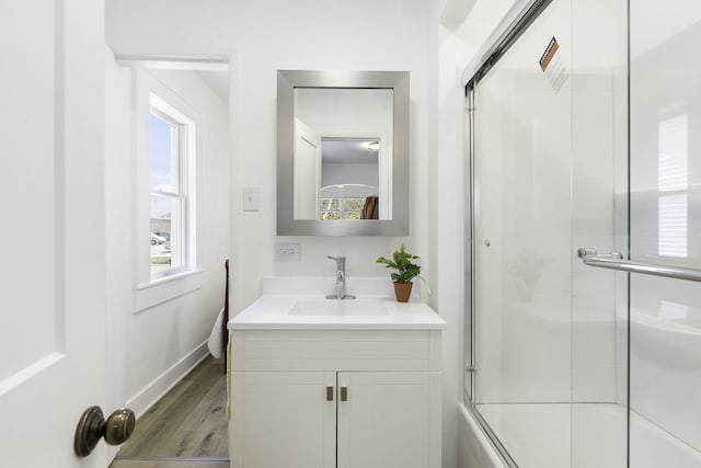 full bathroom featuring baseboards, shower / bath combination with glass door, wood finished floors, and vanity