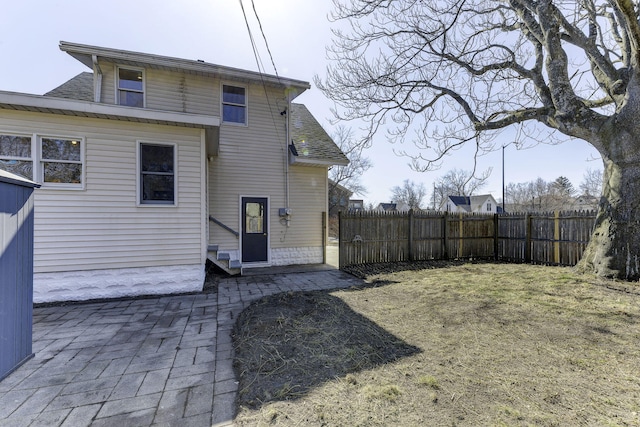 back of house featuring a patio, fence, and roof with shingles