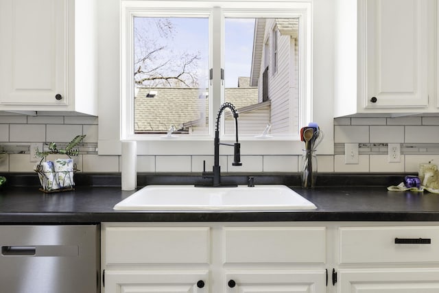 kitchen with a sink, plenty of natural light, stainless steel dishwasher, and dark countertops