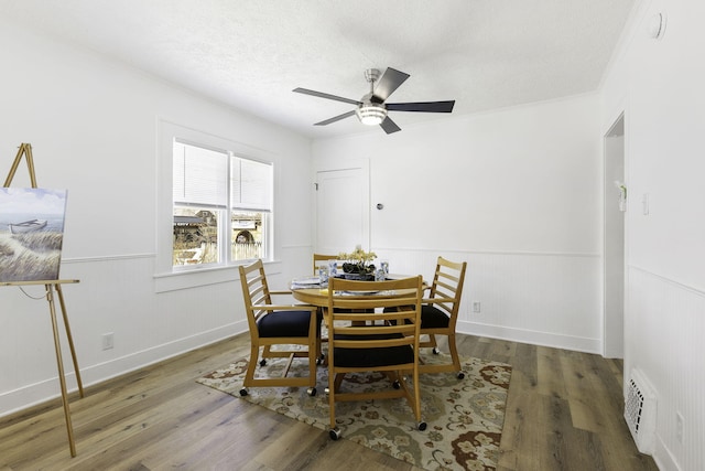 dining area featuring visible vents, a wainscoted wall, and wood finished floors