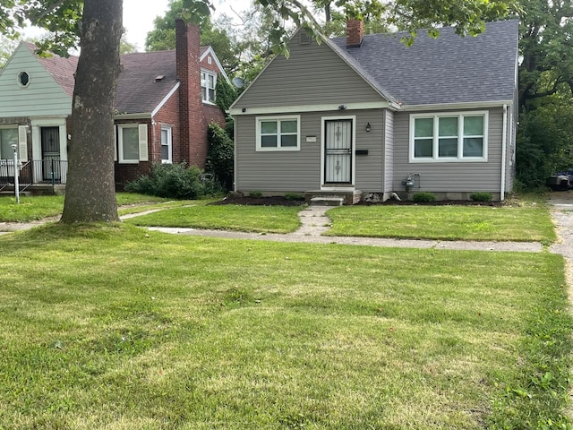 view of front of home with a chimney, a front lawn, and roof with shingles