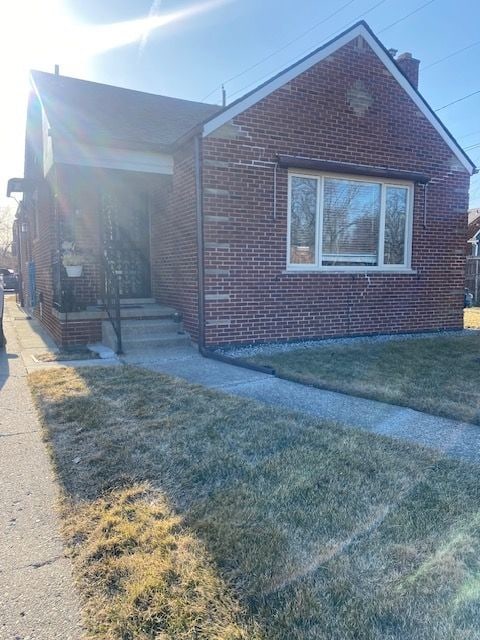 view of front of property featuring brick siding and a front lawn