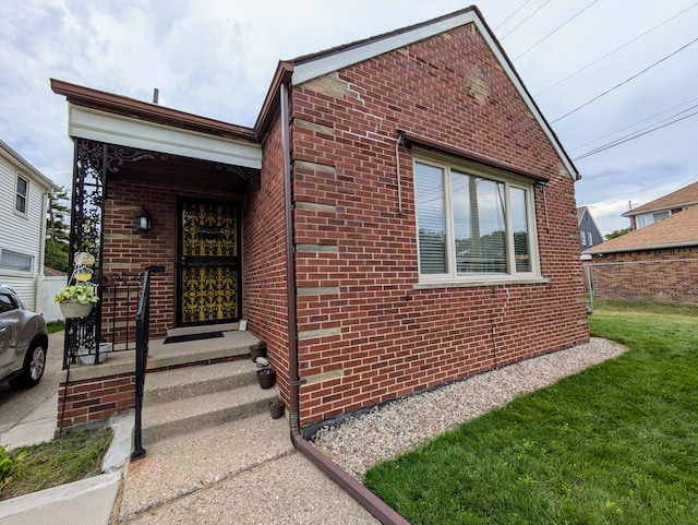 view of front facade with brick siding, a front yard, and fence