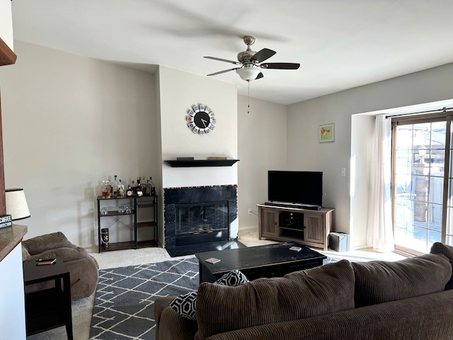 carpeted living room featuring a ceiling fan and a tiled fireplace