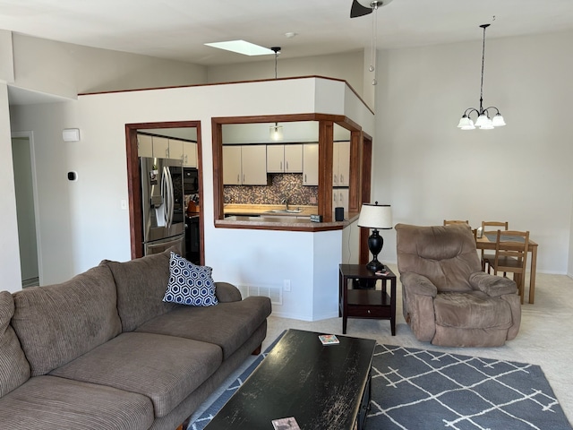 living room with visible vents, carpet, a skylight, and a chandelier