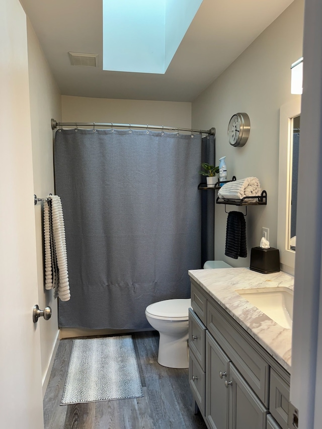 bathroom with vanity, a shower with shower curtain, wood finished floors, visible vents, and toilet