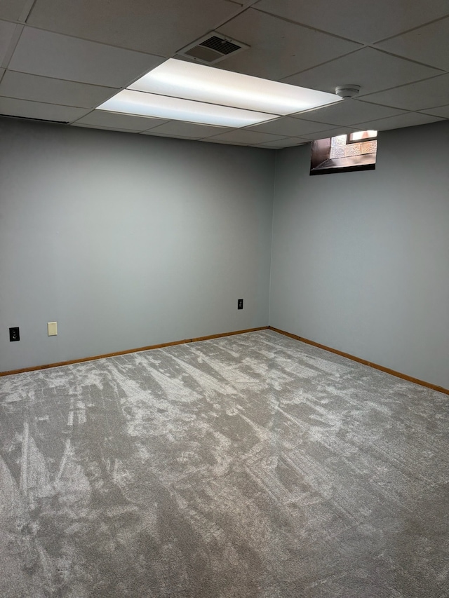 carpeted spare room featuring visible vents, a paneled ceiling, and baseboards