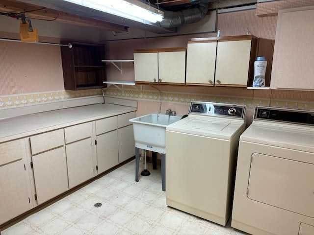 laundry room with washing machine and dryer, cabinet space, light floors, and a sink