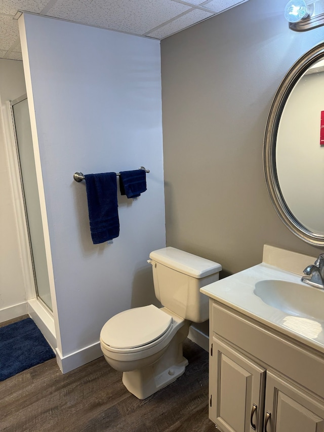 bathroom featuring toilet, wood finished floors, a stall shower, and a drop ceiling