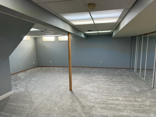 below grade area featuring baseboards, a paneled ceiling, and carpet