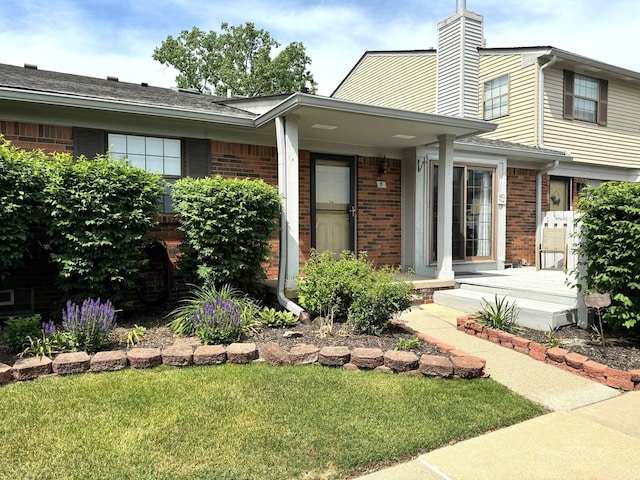 view of front of home with brick siding, a chimney, and a front yard